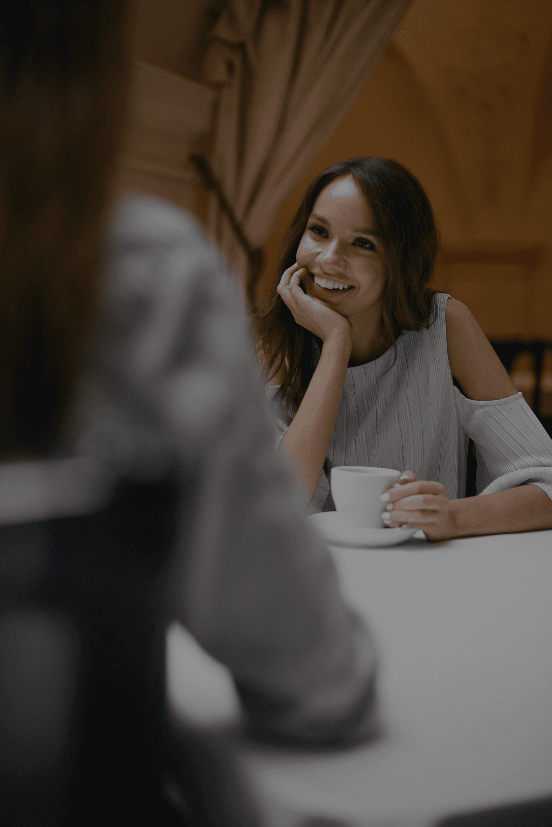 girl smiling and drinking coffee at a table